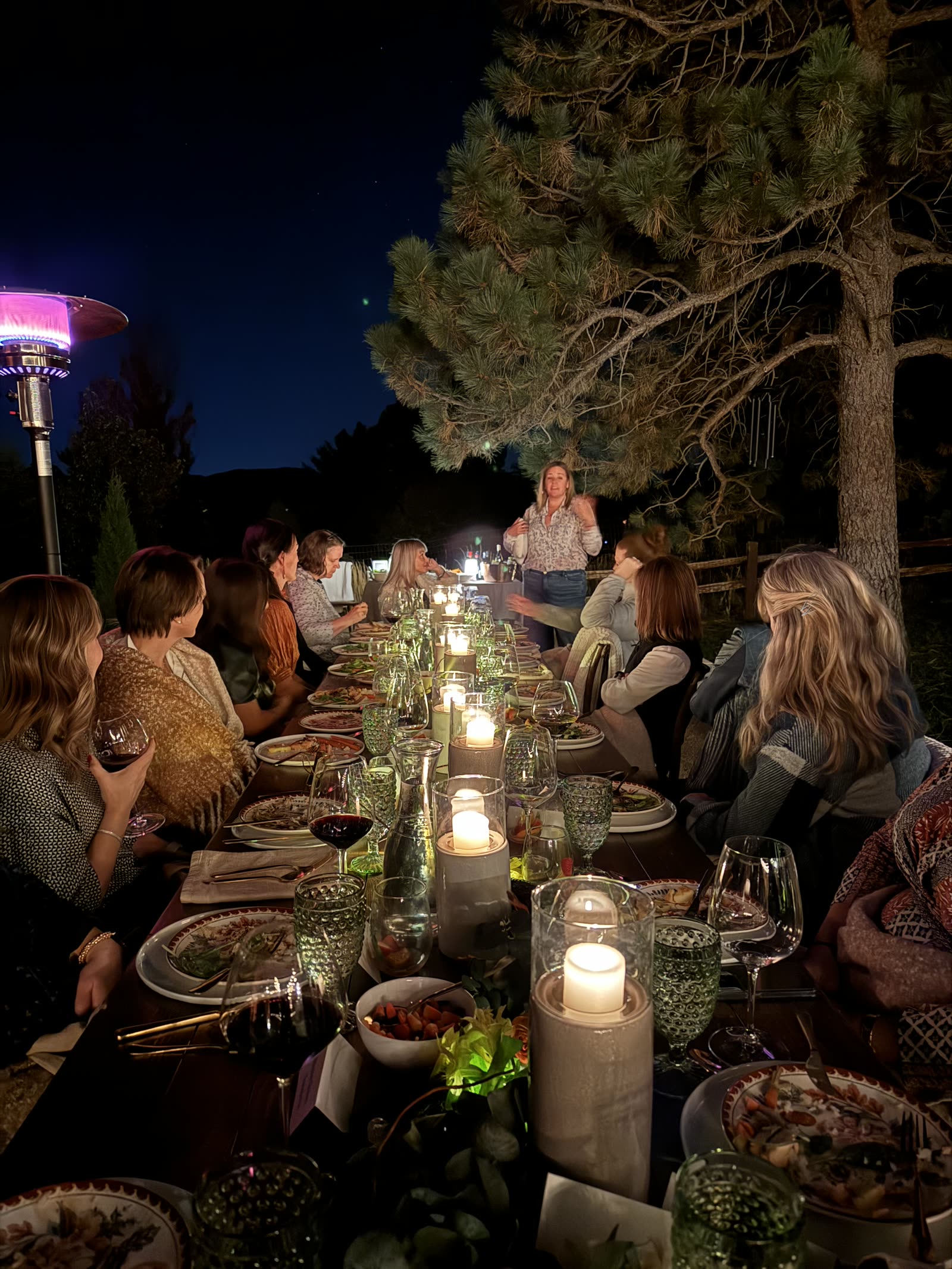 A candlelit Wonder Women dinner table outdoors at night